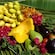 Fresh, whole produce including bananas mangos, tomatoes and a coconut are laid out on a giant palm leaf